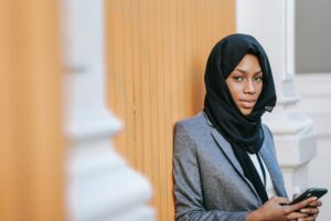 elegant black islamic woman messaging on smartphone and looking at camera
