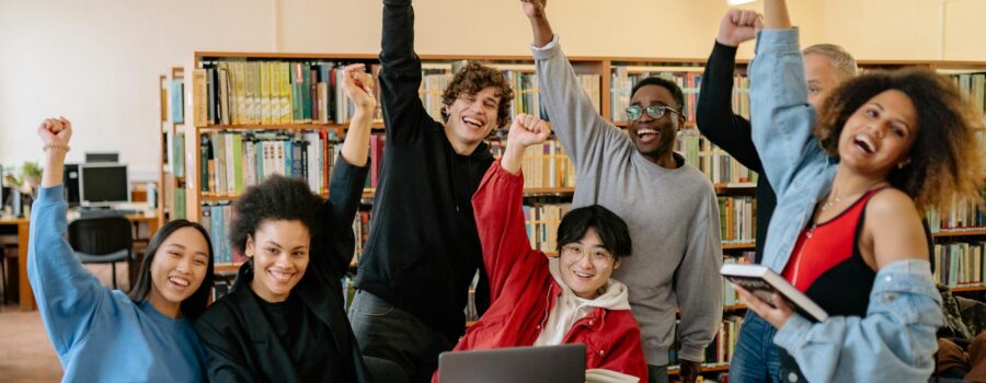 Joyful purpose. group of people smiling and standing near brown wooden table raising hands
