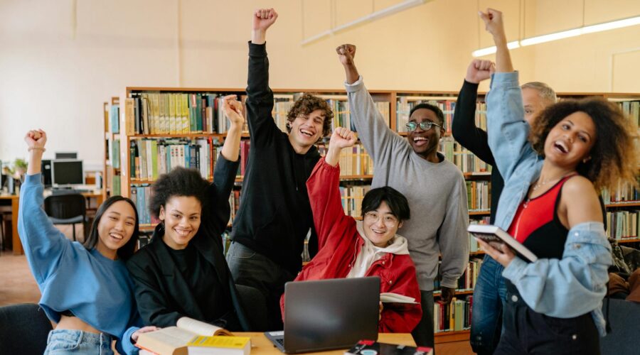 Joyful purpose. group of people smiling and standing near brown wooden table raising hands